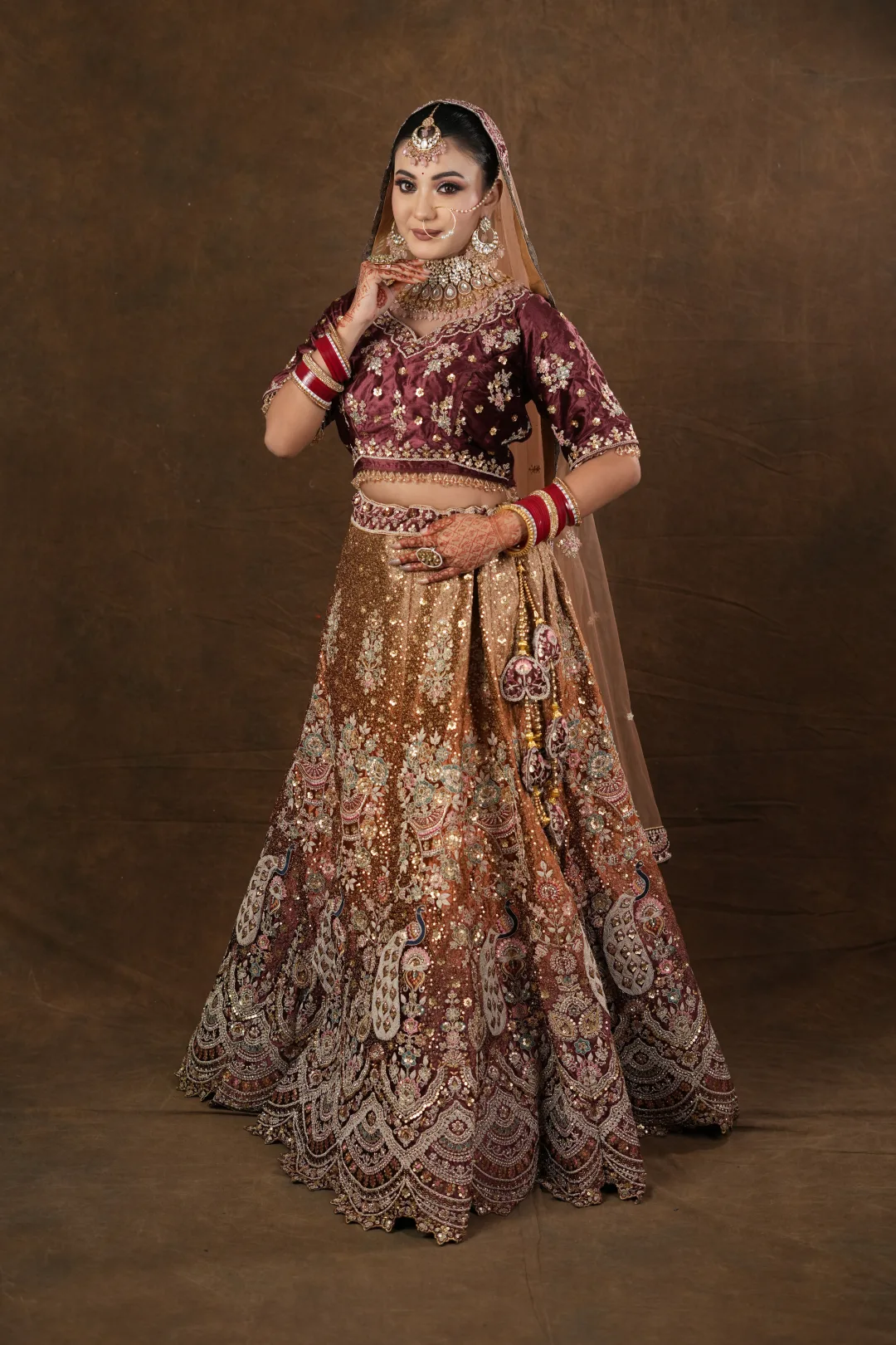 Full-length bridal look in a maroon and gold ensemble.