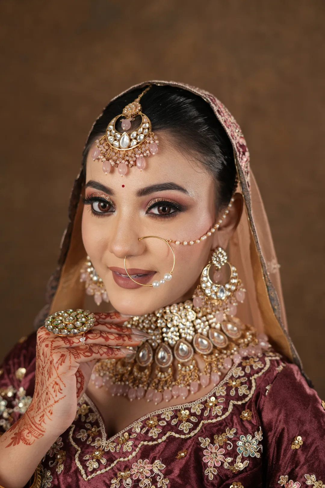 Bridal makeup with rose-gold eyes, a maroon ensemble and traditional jewellery.