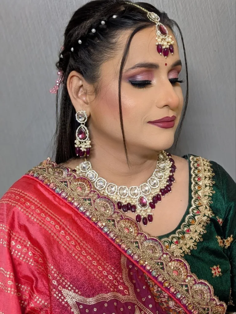 Profile view of a traditional occasion makeup look with pink and green styling.