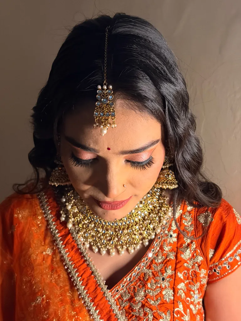 Close view of eye makeup, curled hair and traditional jewellery.